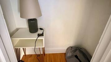 Een kleine kamer met een wit bureau, een lamp en een tas op de vloer.