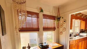 Ein Zimmer mit Holzboden, einem Heizkörper, einem Schreibtisch mit Plattenspieler und einem Fenster mit Jalousien.