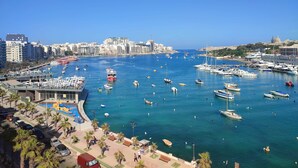A marina with numerous boats, a clear blue sky, and a cityscape in the background. - Designer Penthouse by the Promenade | BBQ Terrace (Gzira)