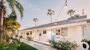 Ein modernes Motel mit einer Reihe von Zimmern, Sitzgelegenheiten im Freien und Palmen.