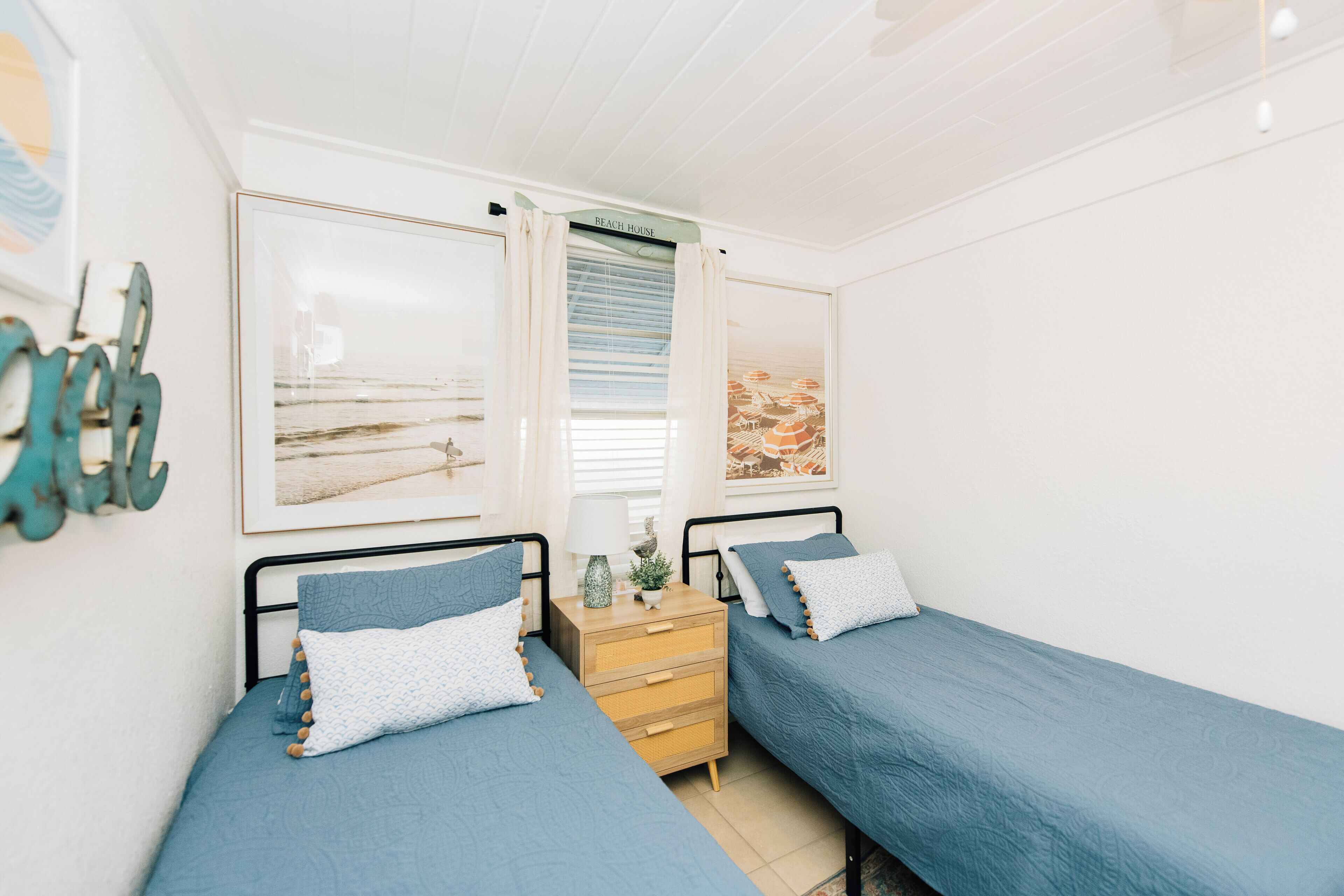 A bedroom with two single beds, a nightstand, and a window with curtains.