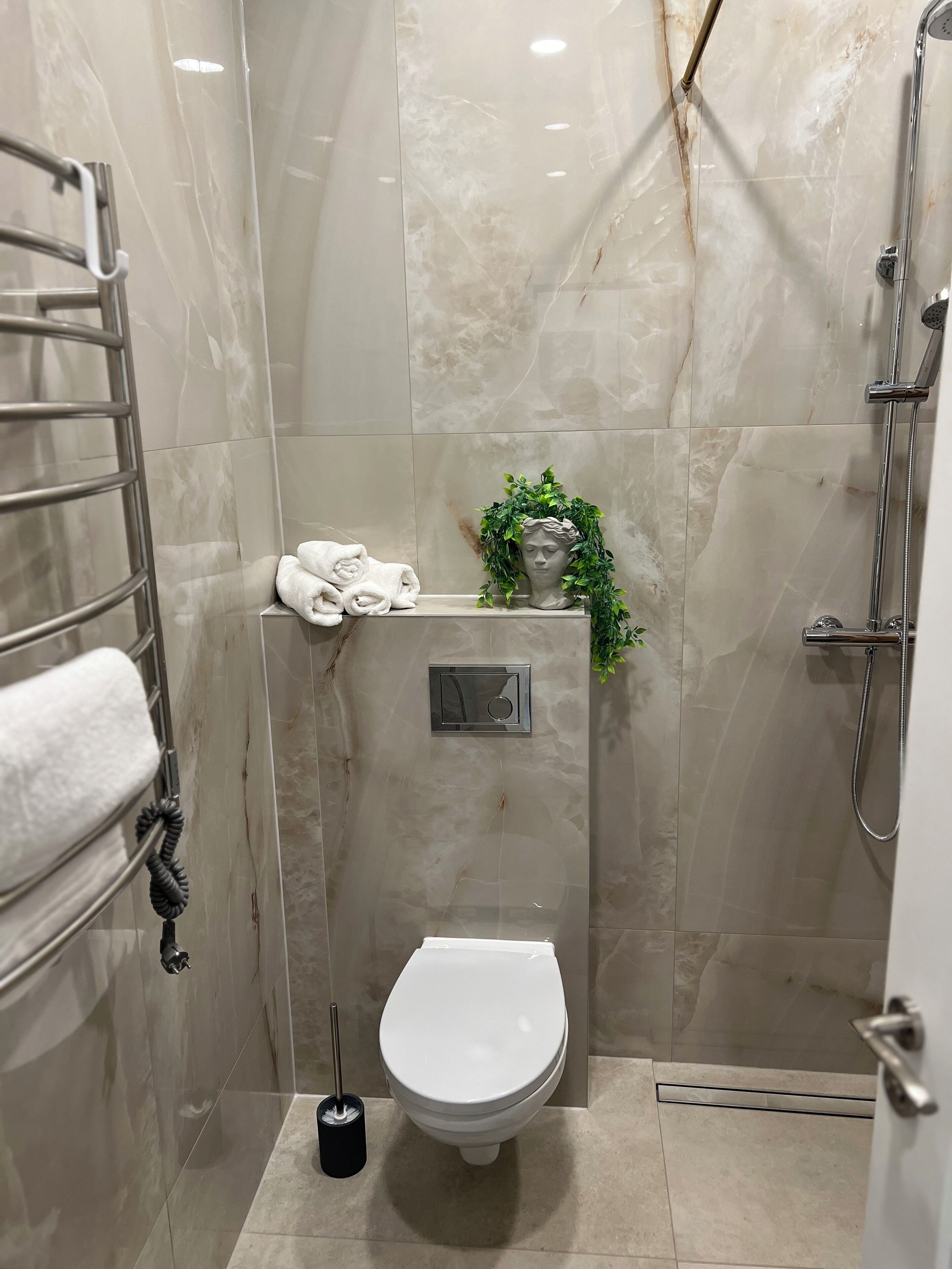 A modern bathroom with a toilet, a shower, and a towel rack.
