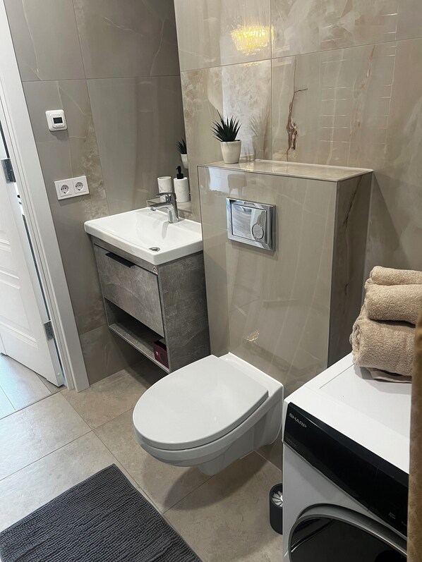 A modern bathroom with a toilet, sink, and built-in washing machine.