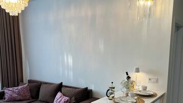 Ein modernes Wohnzimmer mit einem braunen Sofa, einem weißen Couchtisch und einer Kristallleuchtre.