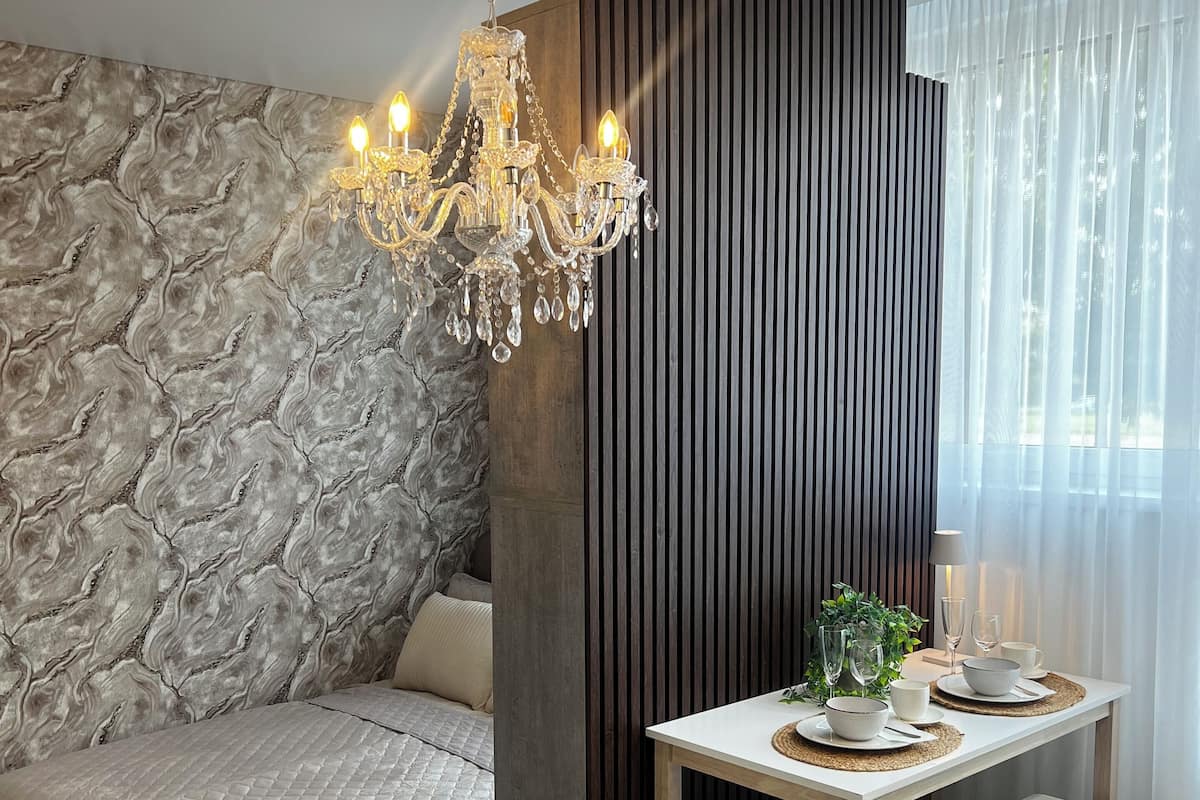 A modern room with a stone wall, a wooden bench, a dining table with chairs, and a chandelier.