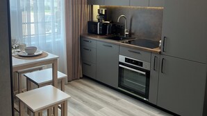 Eine moderne Küche mit Einbauofen, Kaffeemaschine und Spüle. Ein Holzespeisetisch mit Stühlen und einer Kronleuchter sind vorhanden.