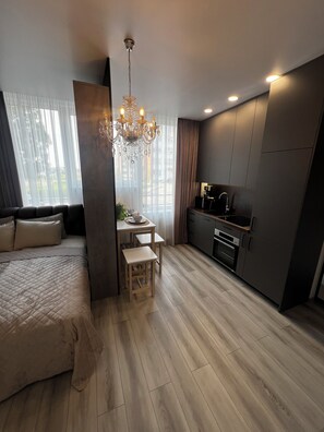 A modern bedroom with a large bed, a small dining table, and a kitchenette.