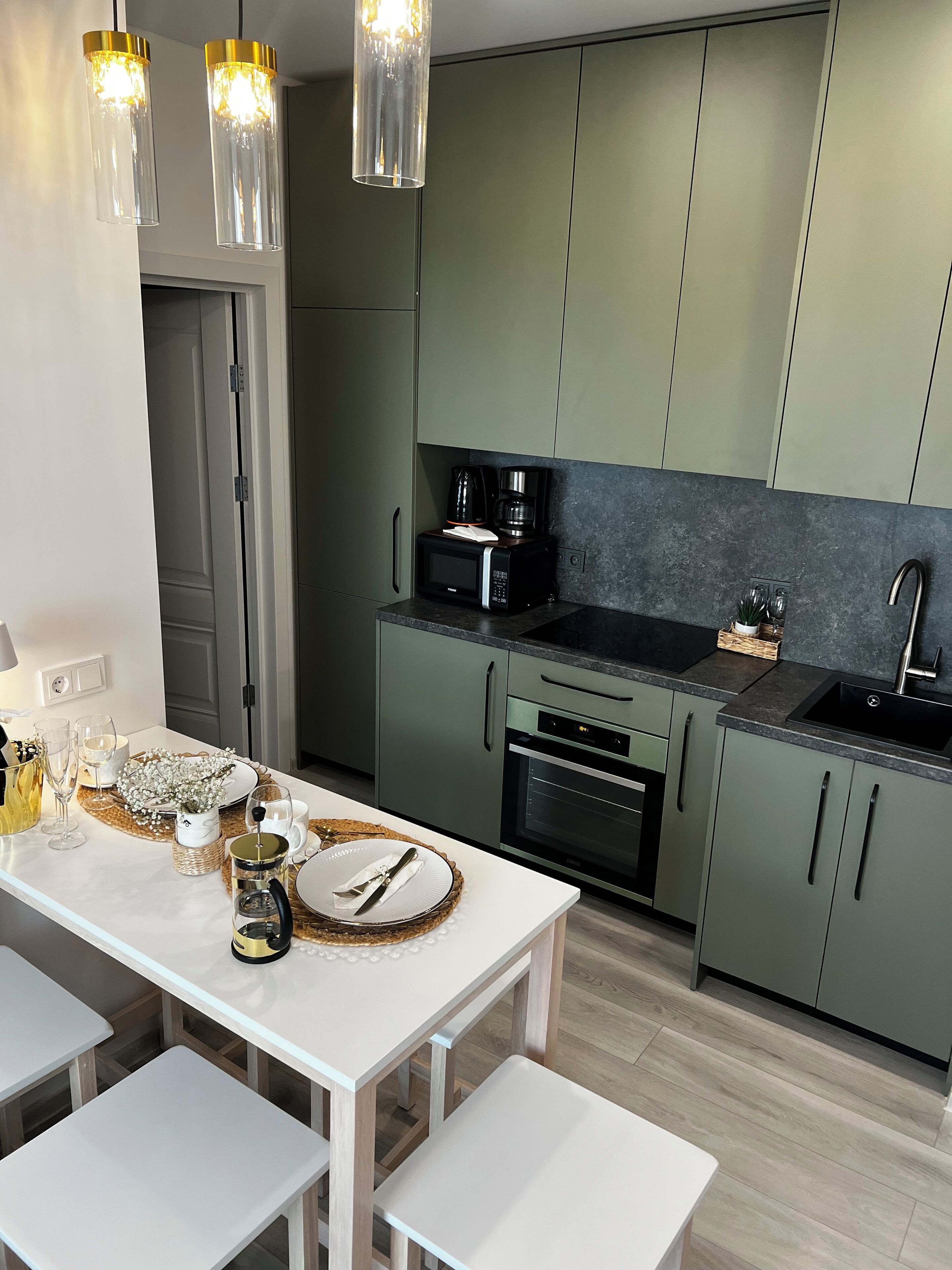 A modern kitchen with a white table set for dining, a coffee maker, and a microwave.