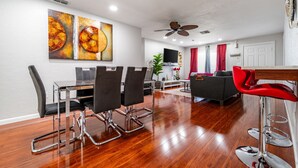 Un salon moderne comprenant un coin repas, un téléviseur et un ventilateur de plafond.