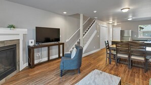 A modern living room with a fireplace, TV, and dining area. - Flexible Extended Stay 3BR - Spacious + Fireplace + Patio (Salem)