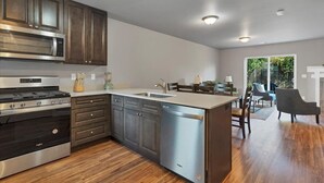A modern kitchen with dark wood cabinets, stainless steel appliances, and a dishwasher. - Flexible Extended Stay 3BR - Spacious + Fireplace + Patio (Salem)