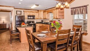 A spacious kitchen with wooden cabinets, a central island, and a dining area with a wooden table and chairs.