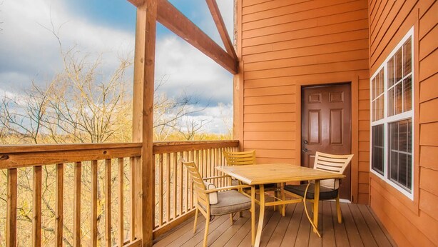 A wooden deck with a table and chairs, a door, and a window.