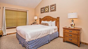 A neatly arranged hotel room with a large bed, bedside tables, and a window with blinds.