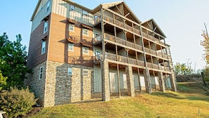 A multi-story building with a stone facade, multiple balconies, and a wooden upper section. - Rustic 2BR Condo w/ Views & Full Kitchen (Pigeon Forge)