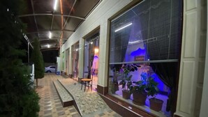 A corridor with patterned flooring, potted plants, and a chair. - HOTEL PLAZA 777 (Samarkand)