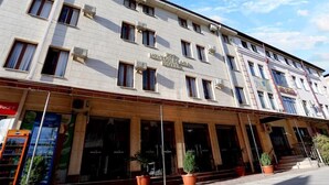 A hotel with a classic facade, multiple windows, and a prominent entrance with steps and potted plants. - HOTEL PLAZA 777 (Samarkand)
