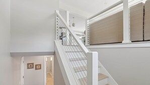 A modern staircase with white railings and wooden steps leading to a second floor. - Surfside Sanctuary at Gooch's Beach (Kennebunk)