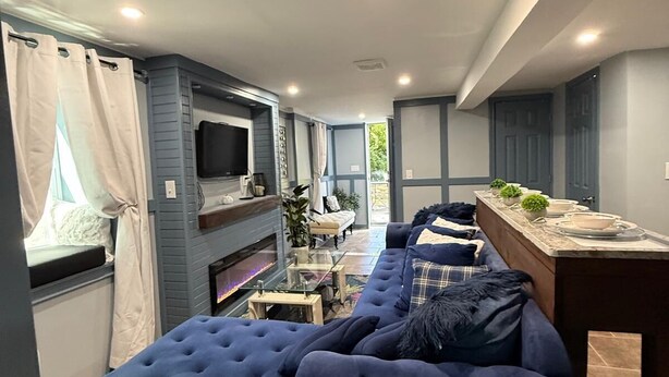 Ein modernes Wohnzimmer mit einer Eckcouch, einem Flachbildfernseher und einem Kamin.