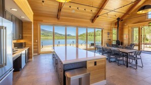 Eine geräumige Küche mit einer großen Kochinsel, Holzboden und großen Fenstern mit Seeblick.