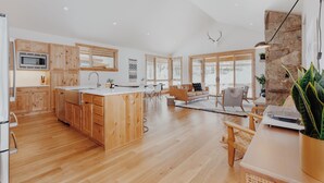 Eine geräumige Küche mit Holzschränken, einer zentralen Kochinsel und einer Wand mit Steinverkleidung.