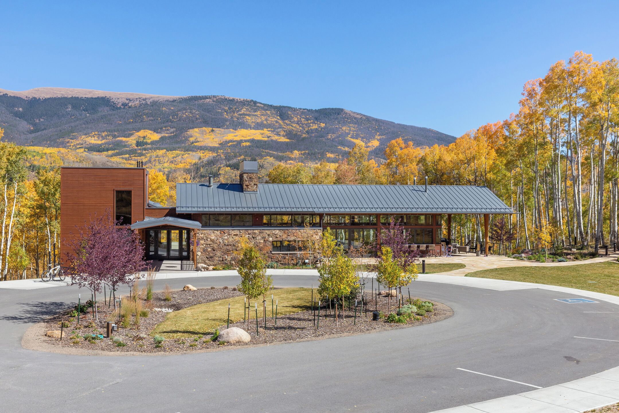 A building with a stone facade, a metal roof, and a parking area with a wheelchair-accessible space.