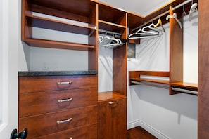 Un vestidor con estantes de madera, cajones y espacio para colgar ropa.