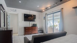 A bedroom with a bed, a dresser, a TV mounted on the wall, and a sliding glass door to the outside. - Welcome To Casa Sabean, a Paradise in Paramira! 4 Bedroom with Pool (Oranjestad)