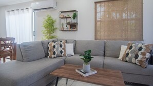 A living room with a grey sofa, a wooden coffee table, and a potted plant. - Welcome To Casa Sabean, a Paradise in Paramira! 4 Bedroom with Pool (Oranjestad)