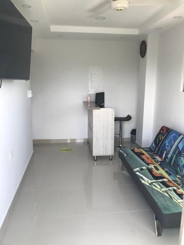 A modern living room with a sofa, a small table, and a TV mounted on the wall. - Hotel Cartagena Sun (Cartagena)