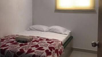 Un dormitorio con cama, ventilador de techo, aire acondicionado, ventana con persianas y puerta.