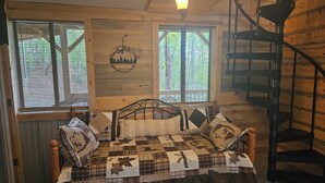 A cozy cabin room with a bed, a window with blinds, a wall-mounted light fixture, and a spiral staircase. - Mountain cabin, gorgeous views! 15 Min to 2 Whitewater Rafting Rivers! feed deer (Murphy)
