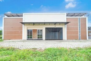 A modern building with a flat roof, large garage doors, and a paved entrance area. - Hotel O Slawi Near Alun- Alu Slawi Formerly Boarding Inn (Slawi)