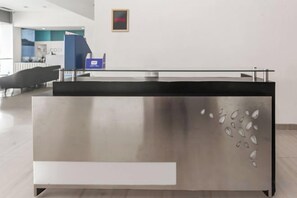 A reception desk with a modern design, a blue counter, and a framed picture on the wall. - Hotel O Slawi Near Alun- Alu Slawi Formerly Boarding Inn (Slawi)