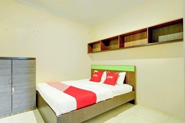 A bedroom with a bed, a wardrobe, and built-in shelves above the bed. - Hotel O Slawi Near Alun- Alu Slawi Formerly Boarding Inn (Slawi)
