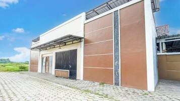 A modern building with a large garage door, a covered outdoor area, and a paved driveway.