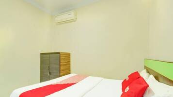 A hotel room with a bed, a wardrobe, and a wall-mounted air conditioning unit.