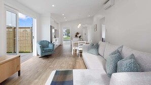 Un soggiorno moderno con un divano, una poltrona blu e un'area pranzo con tavolo e sedie.