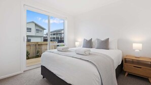 Una camera da letto con un letto grande, un comodino in legno e una porta scorrevole in vetro che dà su un balcone.
