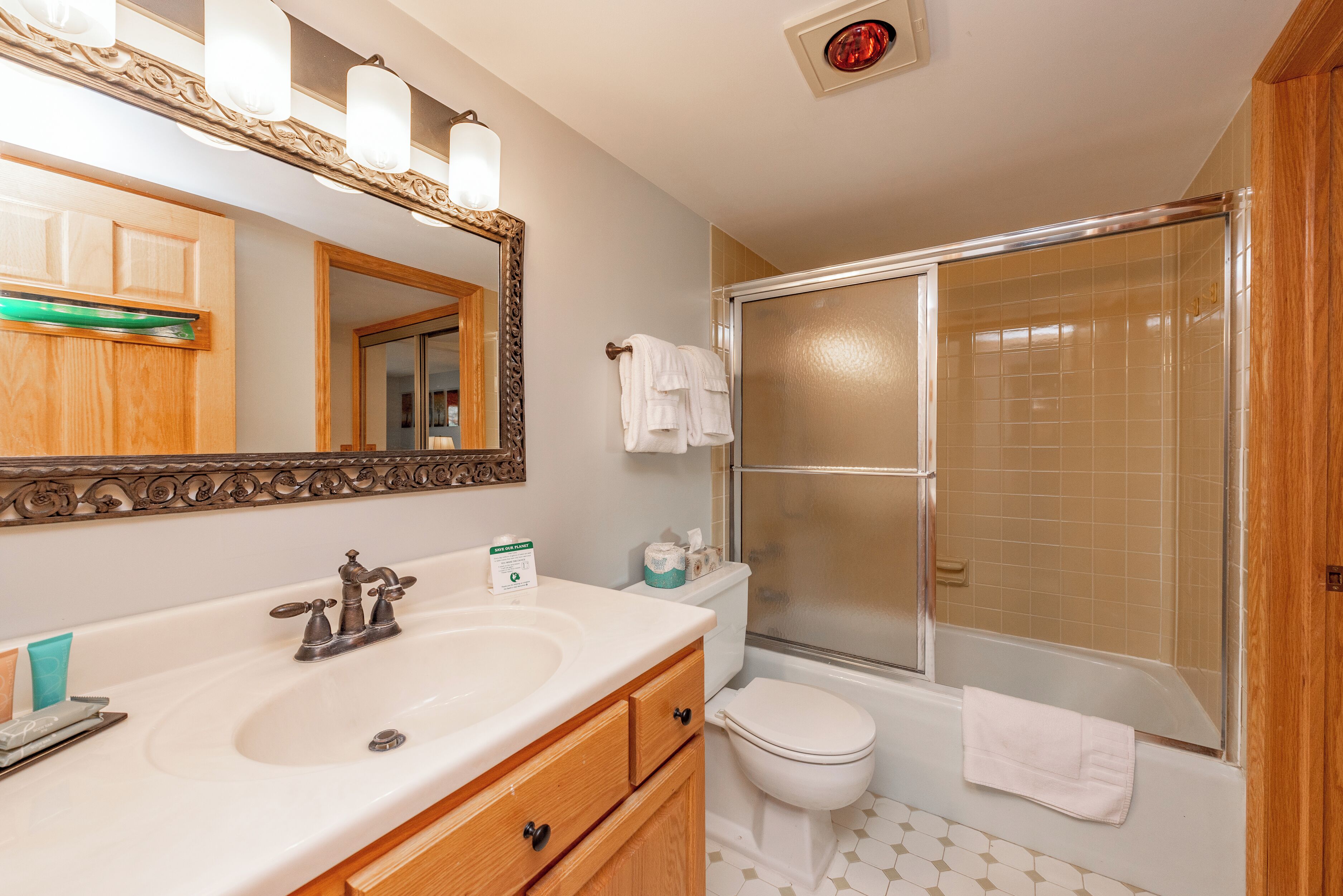 A bathroom with a sink, mirror, toilet, and shower.