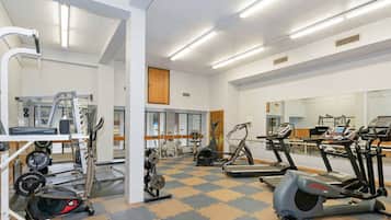 A gym with various exercise equipment including treadmills, elliptical machines, and weightlifting stations.