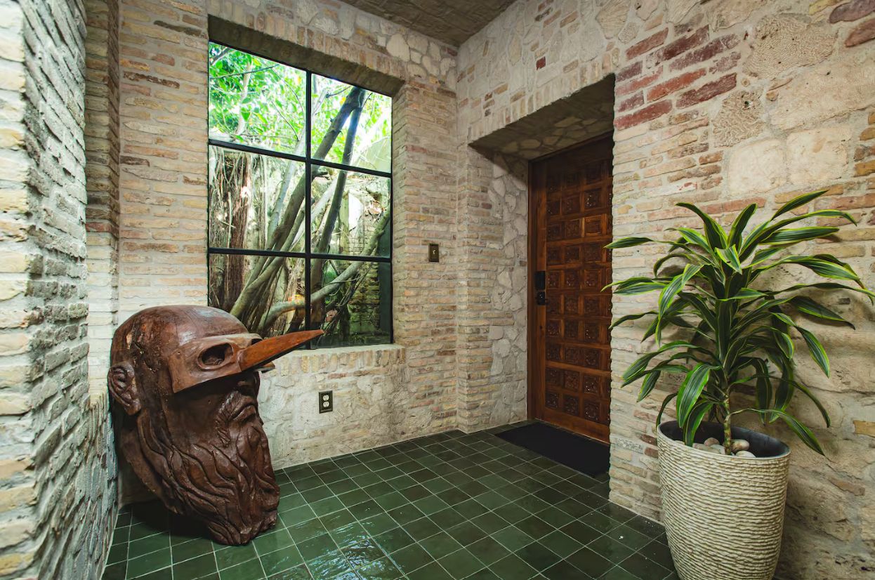 A room with a large window, a wooden door, and a potted plant.
