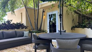 An outdoor seating area with a round table and chairs, a sofa, and an umbrella. - Treehouse - The Canopy (Christiansted)