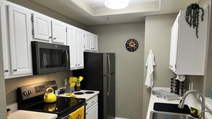 A modern kitchen with white cabinets, a black refrigerator, a microwave, a stove, and a sink. - Dog-Friendly Cozy Condo in North Scottsdale! (Scottsdale)
