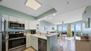 A modern kitchen with stainless steel appliances, a central island, and a view to the outside.
