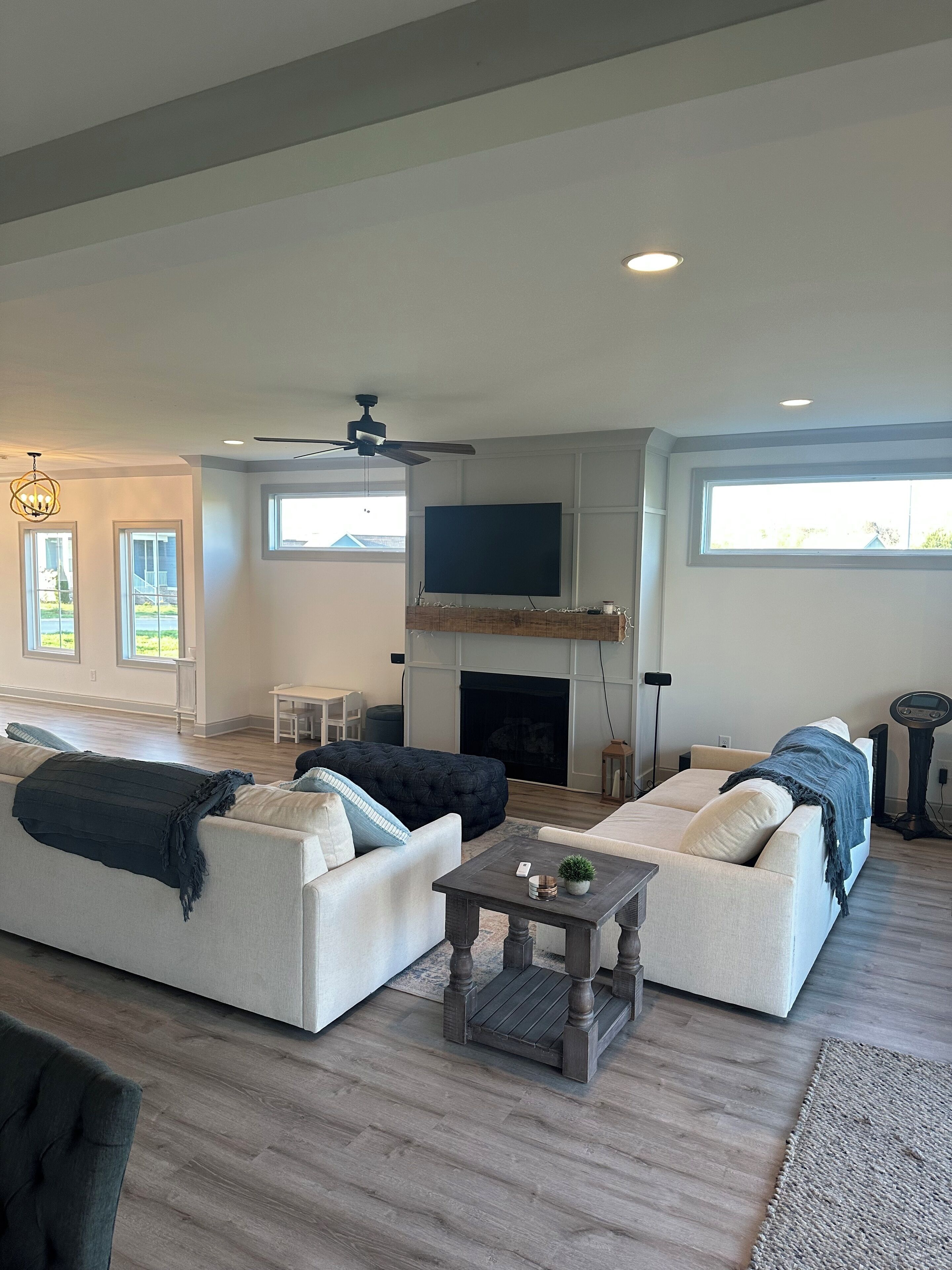A spacious living room with a fireplace, two sofas, a coffee table, and a ceiling fan.