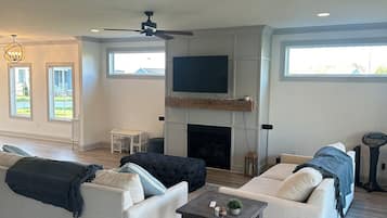 A spacious living room with a fireplace, two sofas, a coffee table, and a ceiling fan.