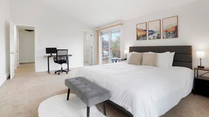 Een ruime slaapkamer met een groot bed, een bureau en een computer.