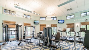 A gym with various exercise equipment, large windows, and a patterned carpet. - 6-bedroom Private Pool House Championsgate (Davenport)