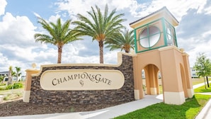 A sign for ChampionsGate with a stone wall and palm trees. - 6-bedroom Private Pool House Championsgate (Davenport)